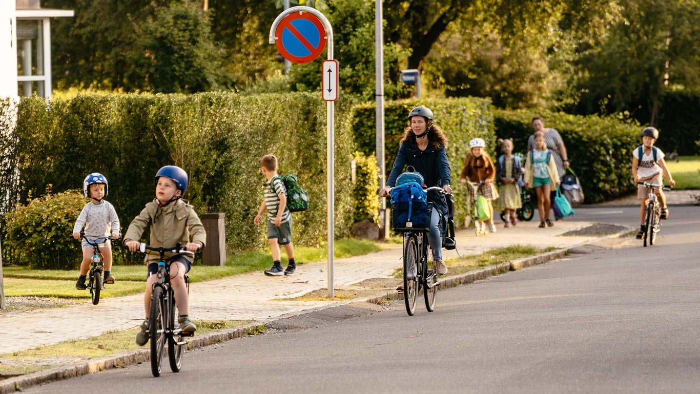 Foto af Thomas Mørkeberg. Børn og forældre cyklende og gående på villavej.